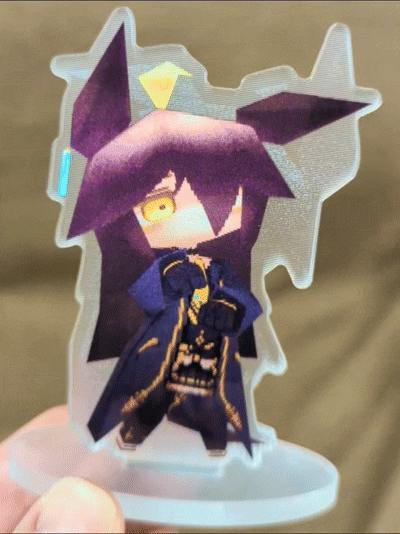 Close-up photo of the lenticular acrylic stand "マンハッタンカフェ" showing the printed character on a round base being held by a hand.