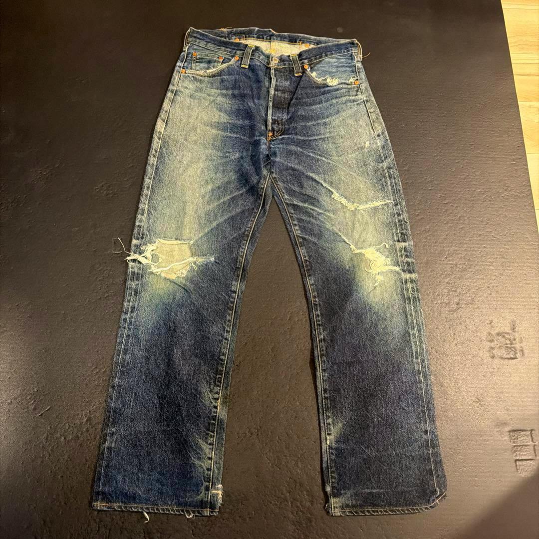 Levi's men's jeans (W36) laid flat on a dark surface showing faded blue denim with rips and wear marks.