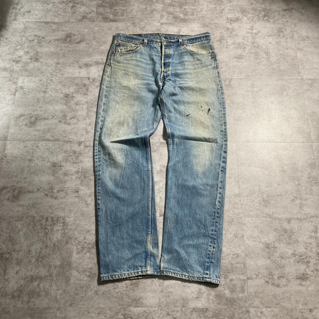 Flat-lay photo of a pair of light blue men's jeans laid flat on a gray surface.