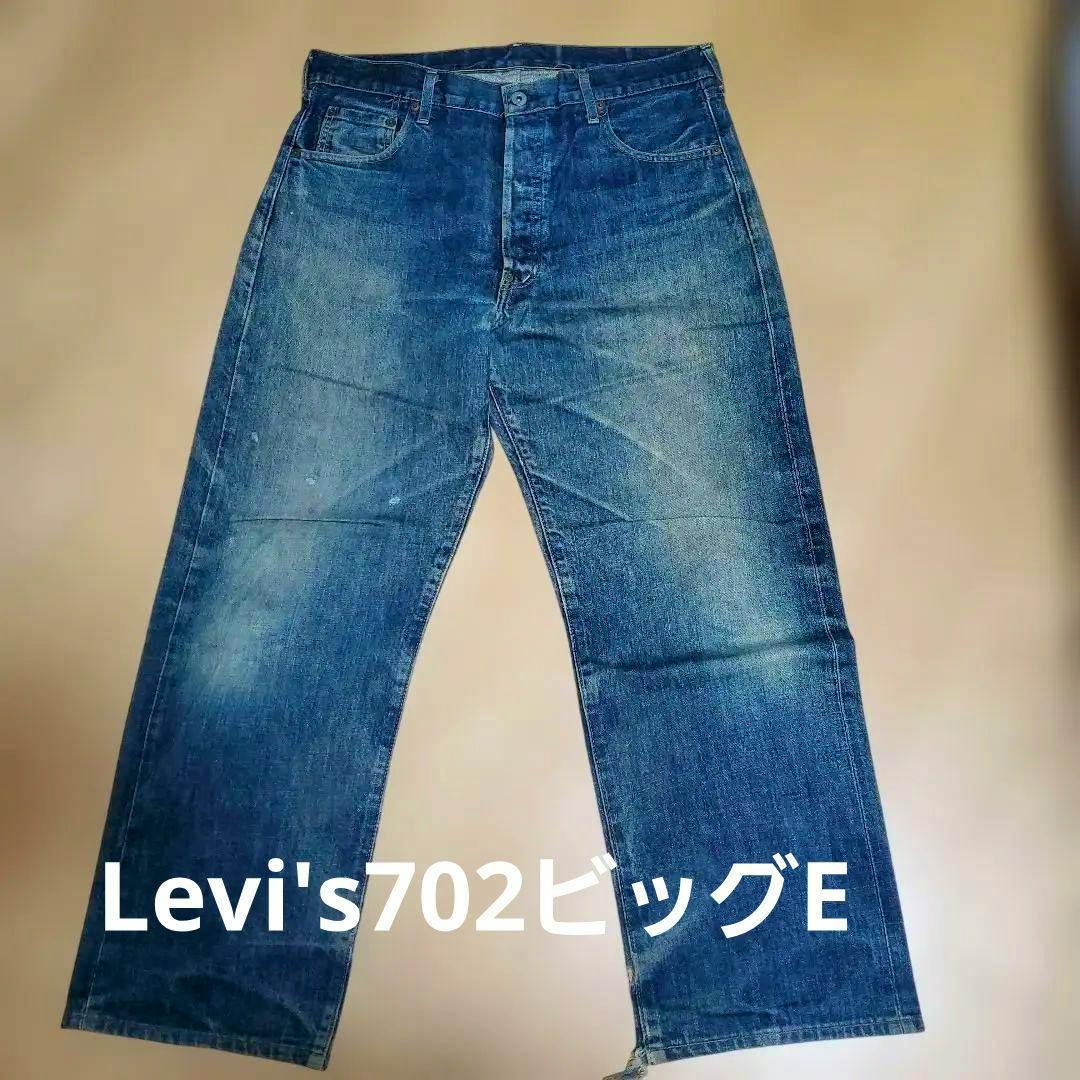 Full-length flat-lay of Levi's 702 men's jeans on a beige background showing the front view with visible fading.