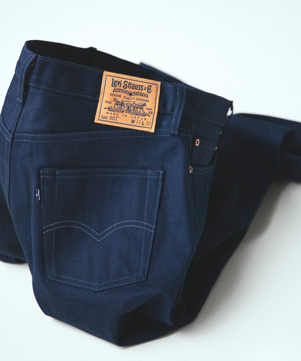Back view of men's Levi's 501 jeans in dark indigo showing the rear pocket, arcuate stitching, and leather brand patch.