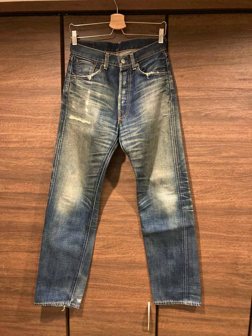 Front view of a pair of men's Levi's blue denim jeans hanging on a hanger, showing button fly, fading, and distressing.