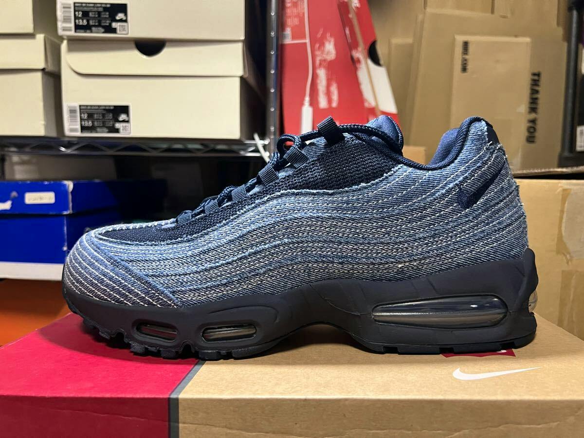 Side profile of a Levi's × Nike Air Max 95 OG indigo denim-blue shoe placed on a shoebox.