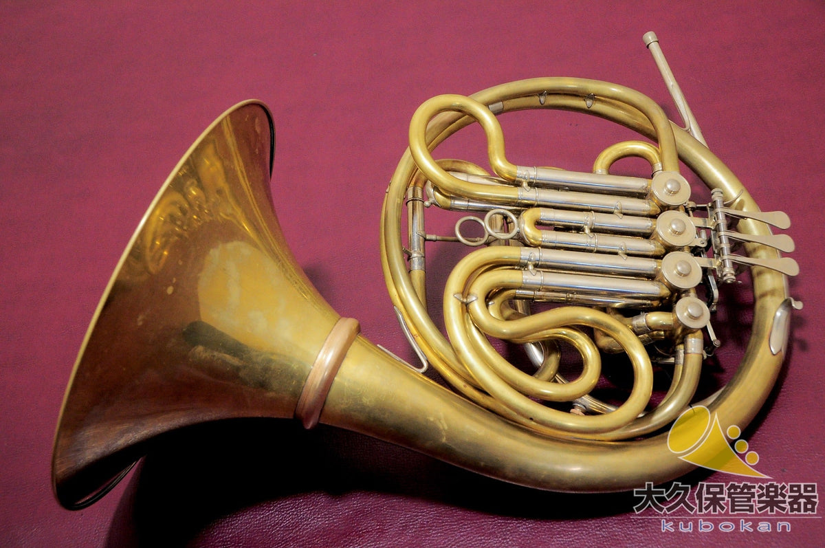 Lewis & Durk LDx5 full double horn with hand-hammered bell resting on a maroon surface, showing valves and coiled tubing.