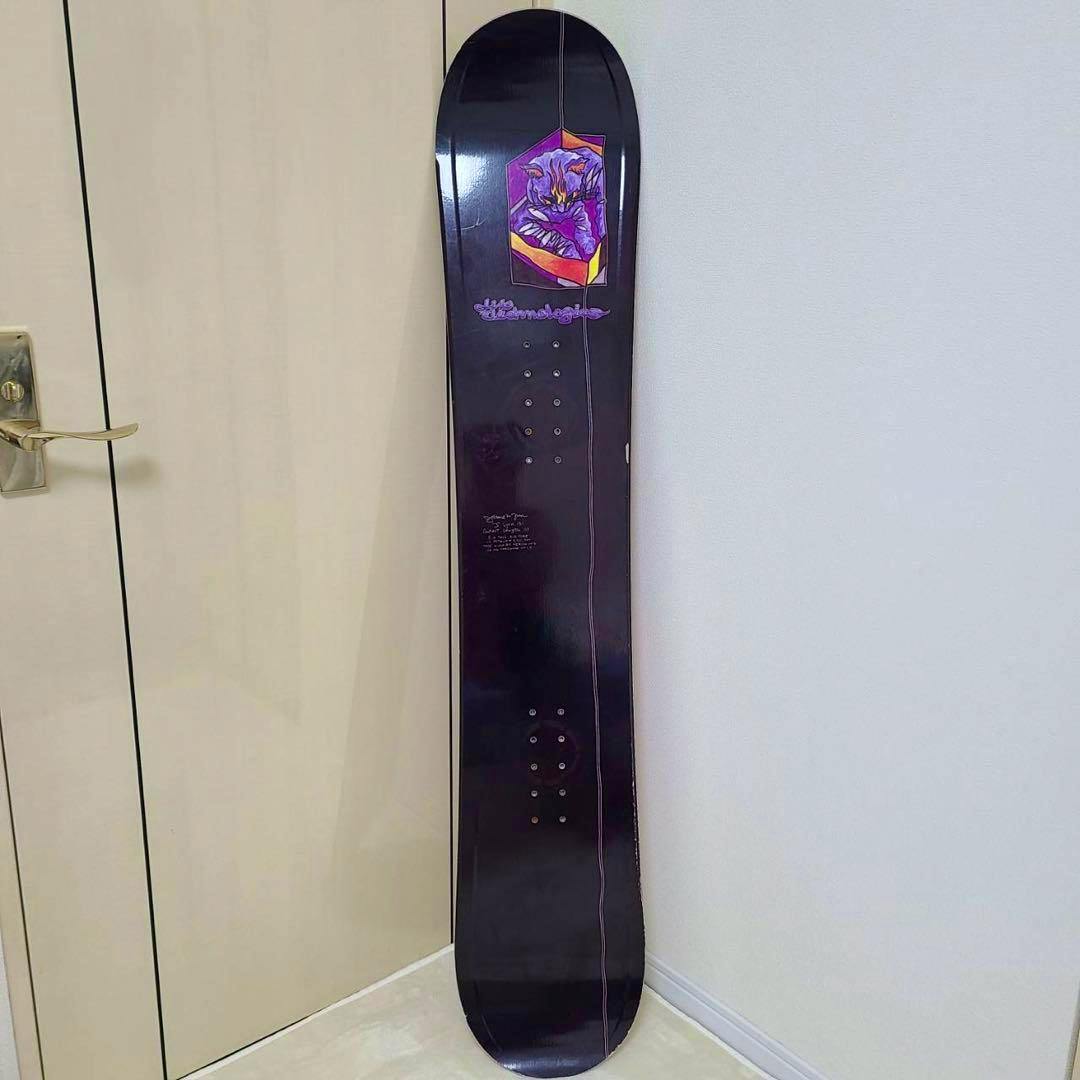 LIB TECH Jamie Lynn “Sleeping Cat” 151cm snowboard standing upright against a wall, showing the top sheet and purple cat graphic near the top.