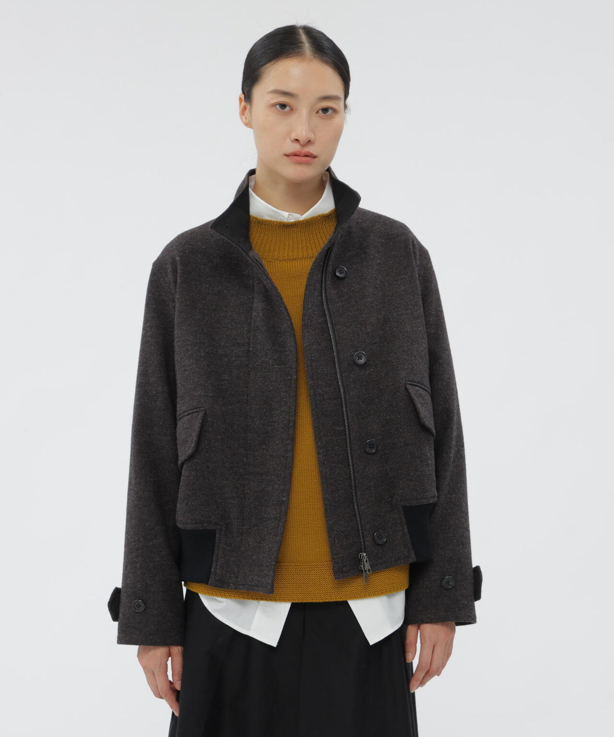 A front view of a model wearing a dark gray light British wool blouson over layered clothing.