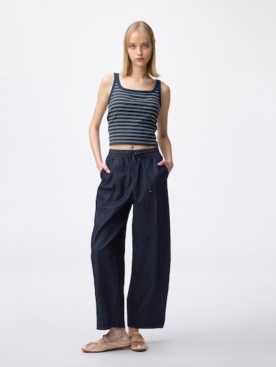 Front view of a model wearing the light denim barrel ankle pants with hands in pockets.