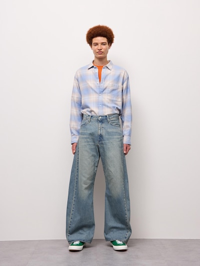 Male model shown full-length wearing the light denim barrel-leg jeans.