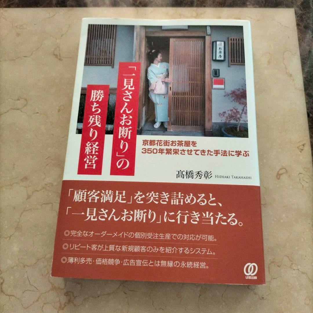 Front cover of the book showing the Japanese title and a photograph of a woman in a kimono standing at a wooden doorway.