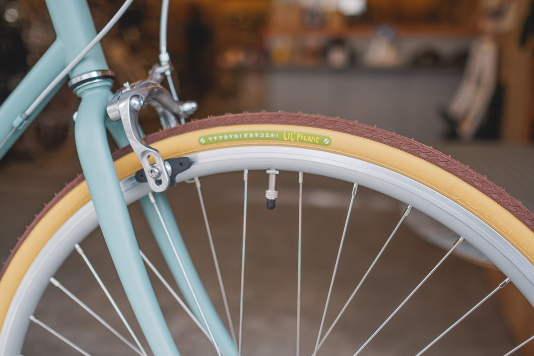Front bicycle wheel fitted with the LIL’PICNIC pop grumpy bicycle tyre in tan and brown mounted on a light blue fork.