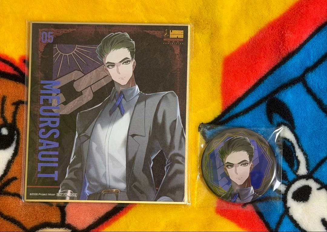 Packaged Limbus Company shikishi (illustration board) and a sealed round can badge showing the same character, placed on a colorful blanket.