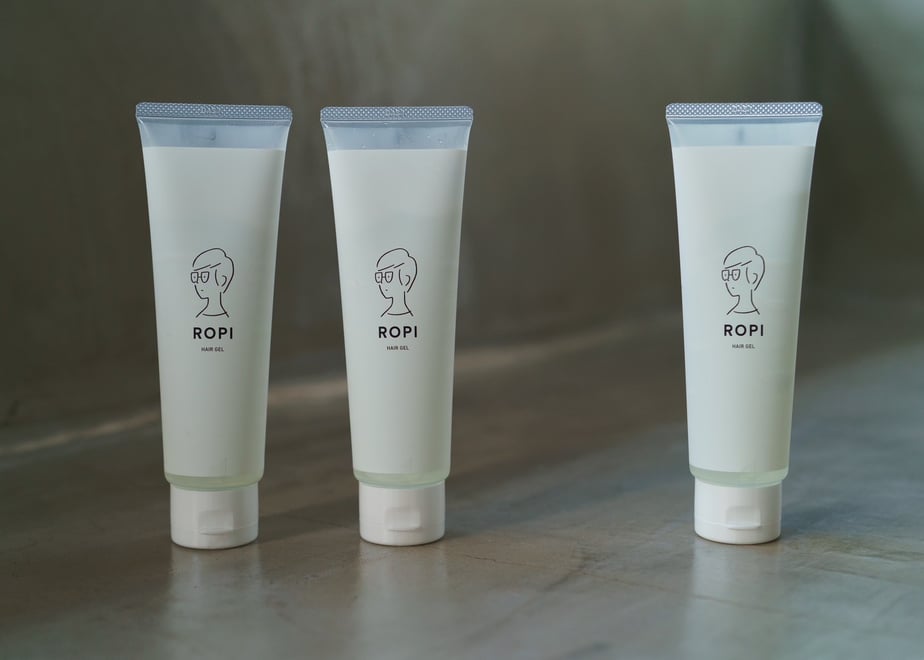 Three upright tubes of hair gel labeled “ROPI” arranged on a smooth surface.