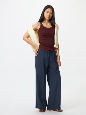 A woman modeling navy wide-leg women’s pants against a white background.
