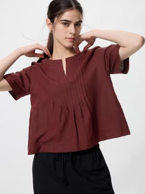 Model wearing the linen-blend key-neck women's blouse with short sleeves and front pintuck detailing.