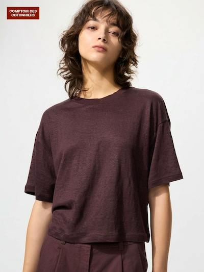 Model wearing a women's boxy short-sleeve T-shirt in a dark burgundy color shown from the waist up.