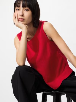 Model seated on a stool wearing the listed red women's relaxed-fit T-shirt.