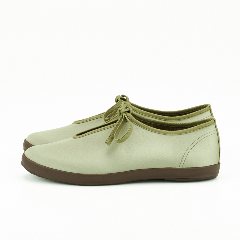 Side view of a pair of LITE PRIM M polyester shoes in light green with brown soles and tied bows on a white background.
