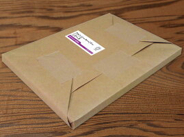 Packaged A4 LKカラーN-FS white paper wrapped in brown cardboard with a product label on a wooden surface.