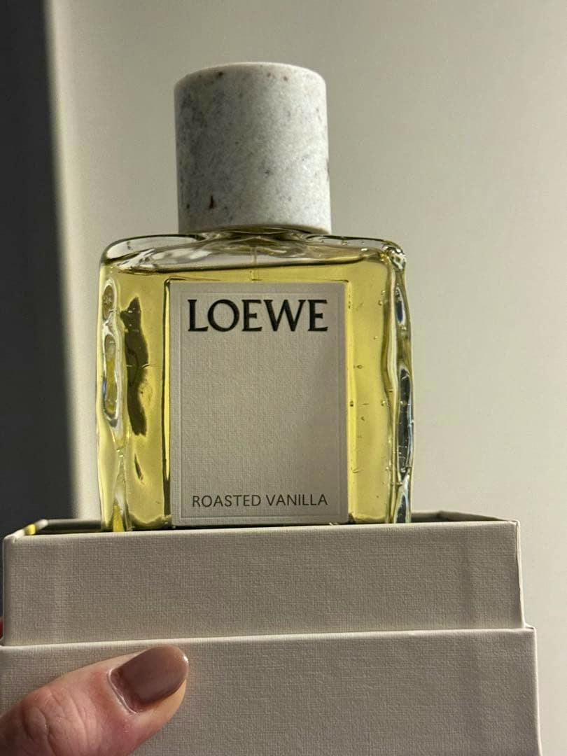 Front view of the LOEWE Roasted Vanilla perfume bottle showing its label and marble-like cap atop a white box.