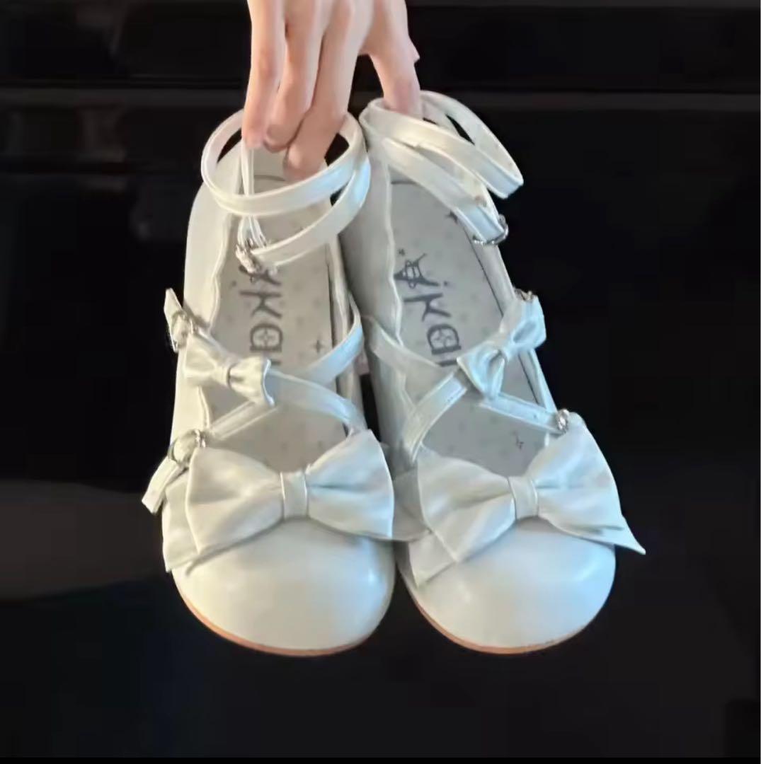 Lolita plastic sandals (size 25.5) pair with front bows held by a hand against a black background.