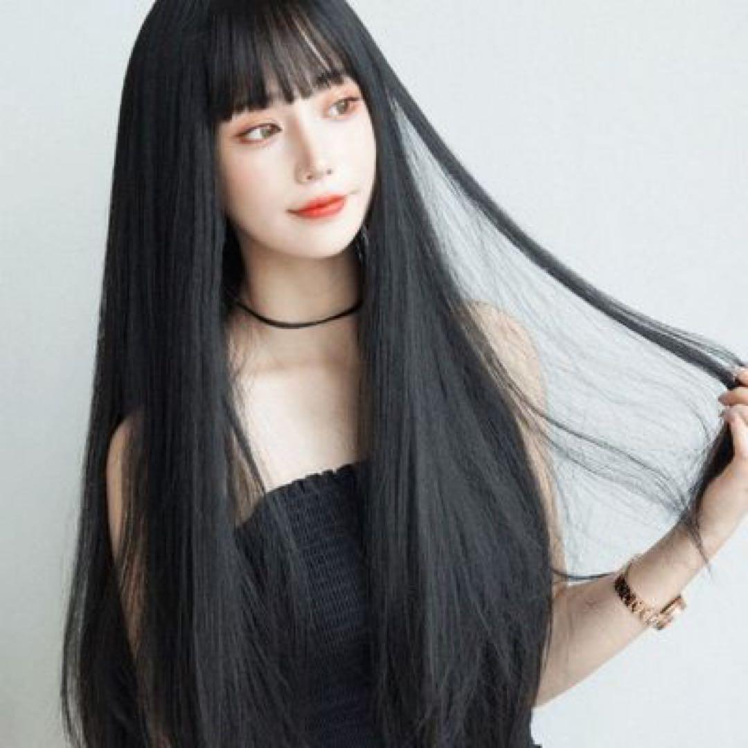 A model wearing a long straight black wig with bangs, shown from the front and side.