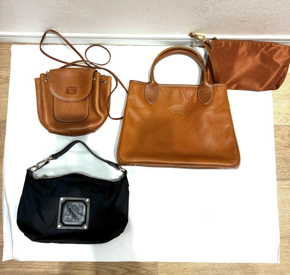 Top-down photo of the three listed bags (two Longchamp and one Burberry) laid out on a white background.