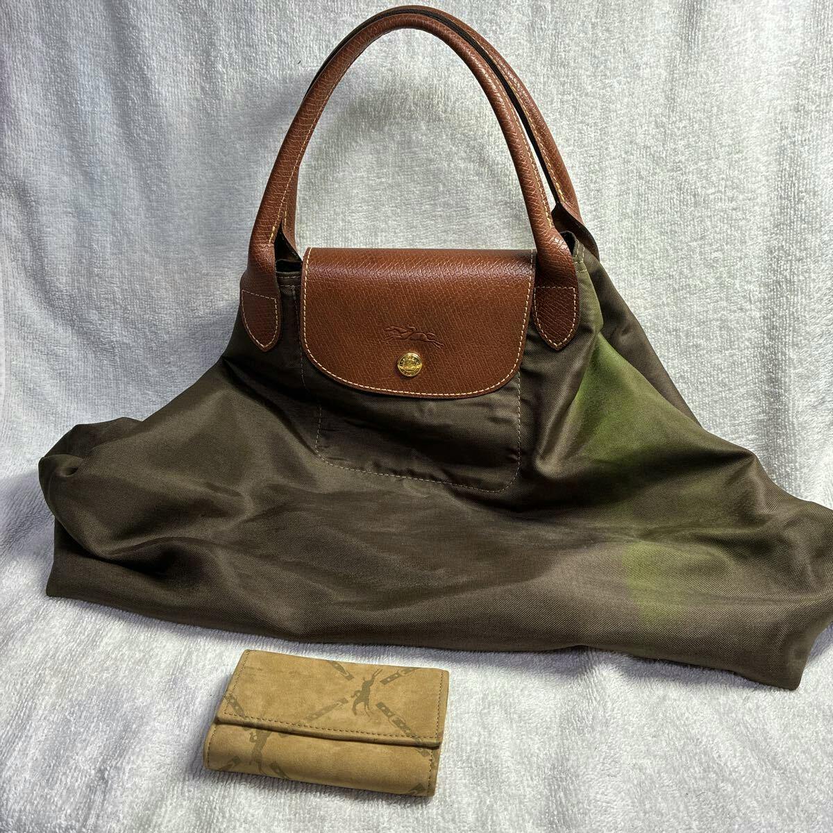 Brown Longchamp nylon shopping bag with brown leather flap and handles shown with a small brown key case on a light background.