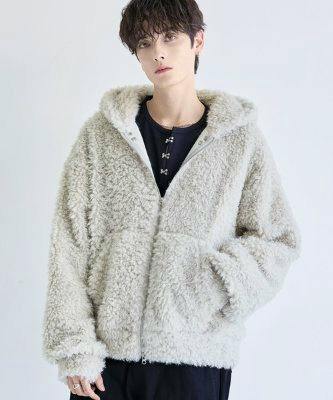 Model wearing a loose-silhouette fluffy zip-up hooded jacket shown from the front with hands near pockets.