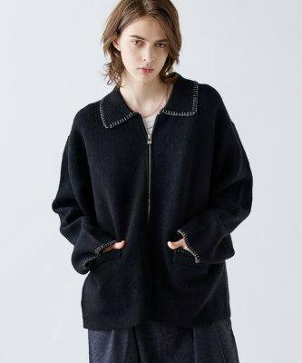 Model wearing a loose-fit black zip-up sweater with a collar, front pockets, and visible stitch detailing at the collar and cuffs.
