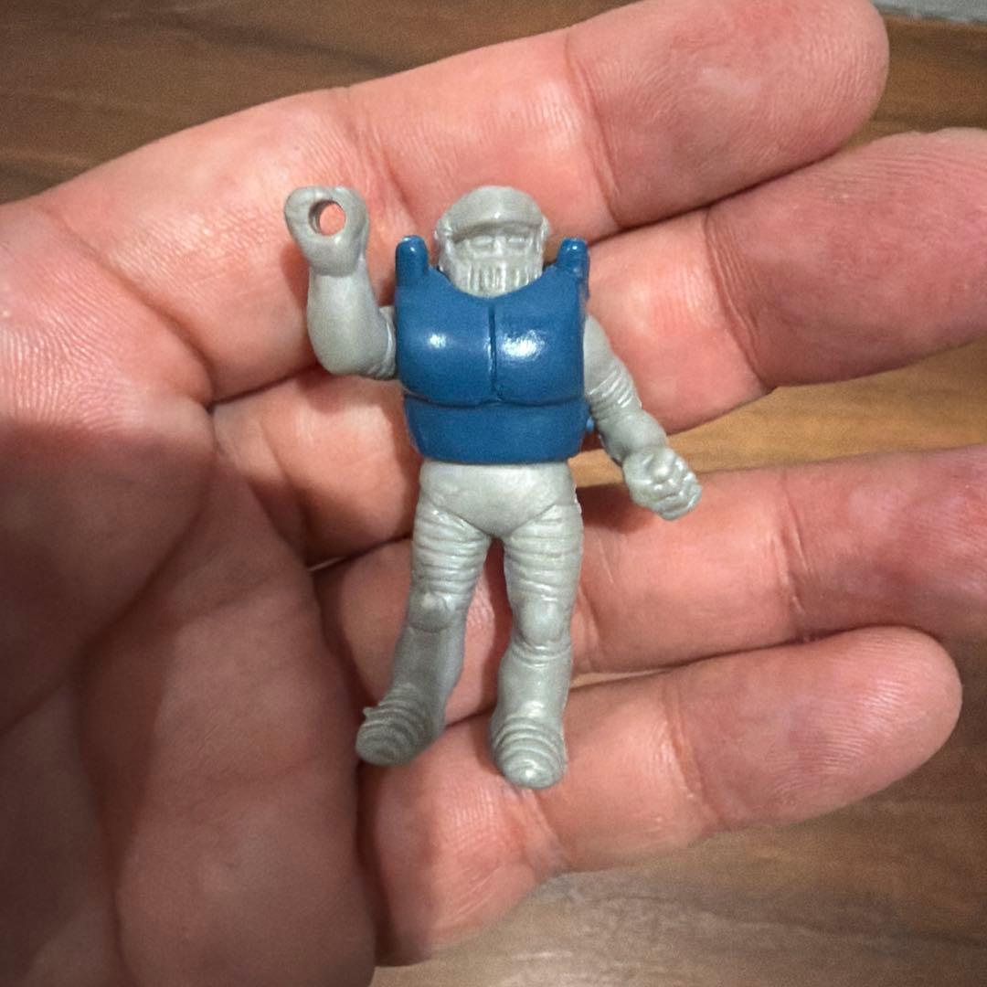A hand holding a small gray-and-blue eraser figure.