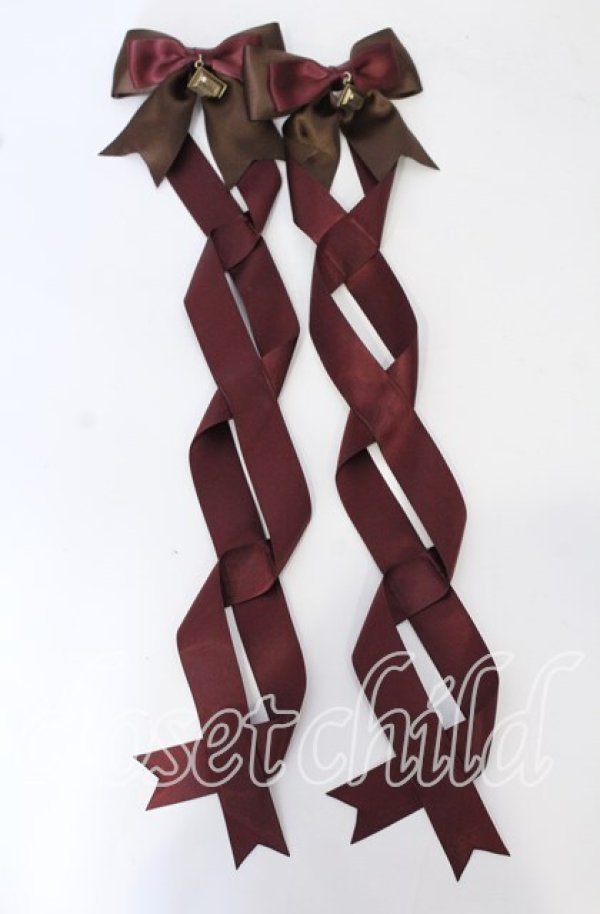 Two chocolate and wine-colored twin-tail ribbon barrettes with bows and long braided tails on a white background.