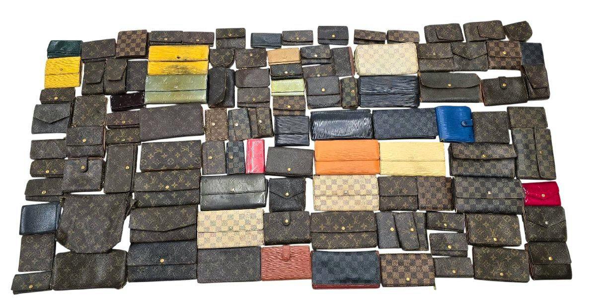 A large assortment of Louis Vuitton wallets and small leather cases laid out flat on a white background, showing various monogram, Damier, Epi, and Vernis styles.