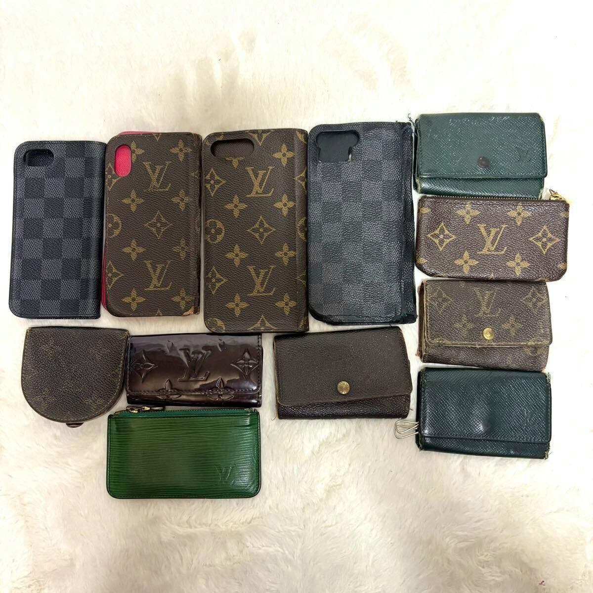 12-piece set of Louis Vuitton wallets, key cases, and phone cases in various monogram, Damier and green leather arranged on a light surface.
