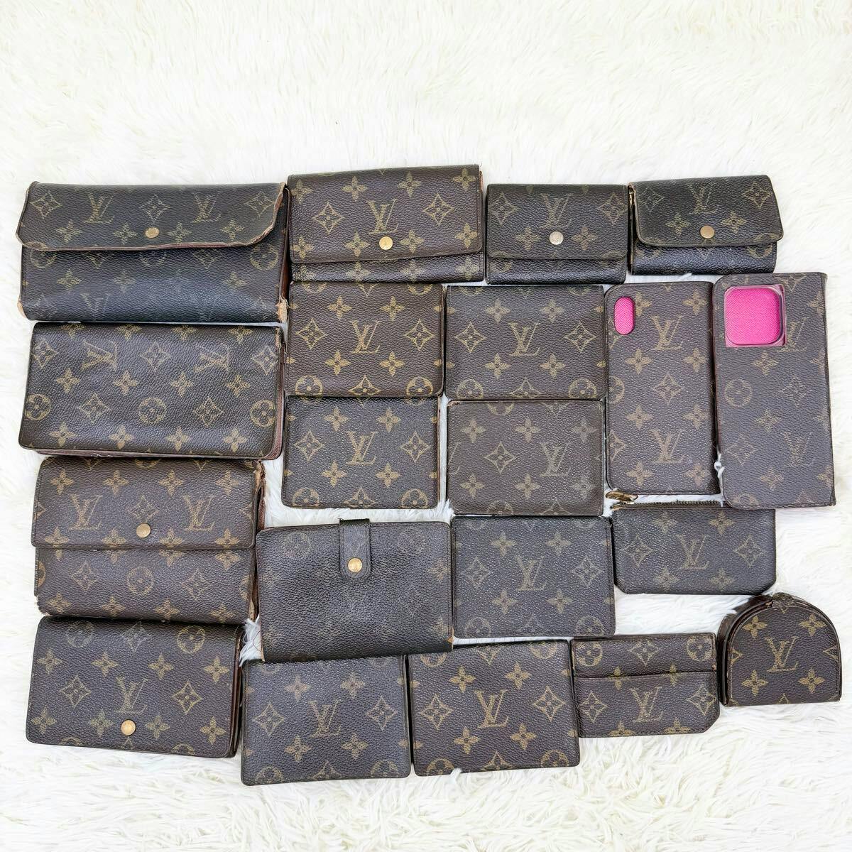 A flat lay of many Louis Vuitton monogram wallets and small leather goods arranged on a white background.