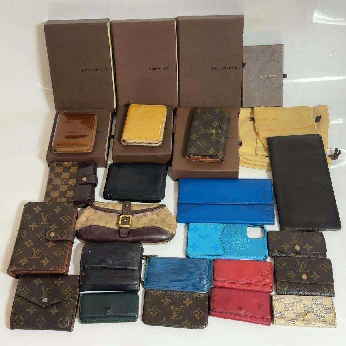 Assorted Louis Vuitton wallets and small leather goods arranged on a surface with several Louis Vuitton boxes and dust bags.