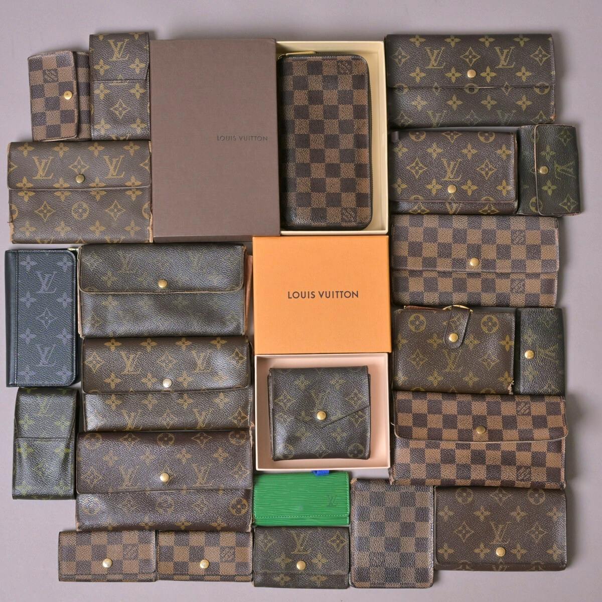 Flat lay of multiple Louis Vuitton wallets and small leather goods in Monogram and Damier patterns arranged with two Louis Vuitton boxes.