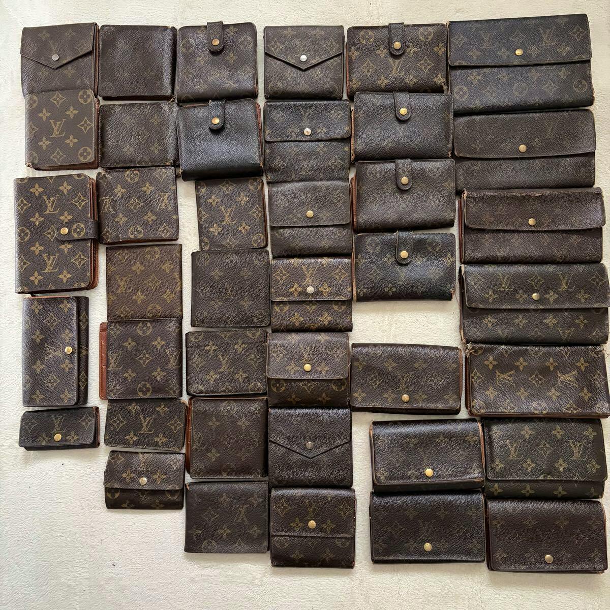 Multiple Louis Vuitton monogram wallets and small cases arranged on a light surface.