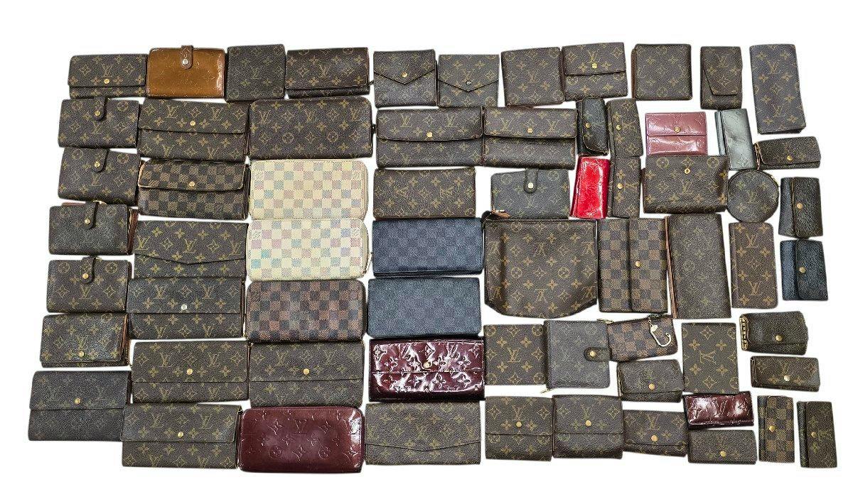 Multiple Louis Vuitton wallets and small leather goods in monogram, Damier, and vernis styles arranged on a white background.