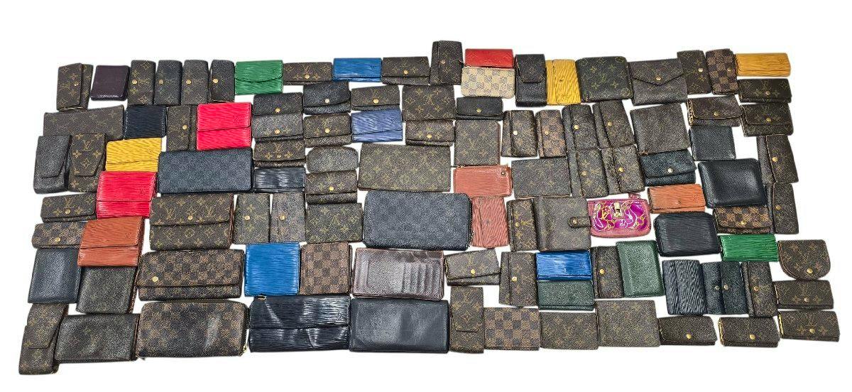 A large assortment of Louis Vuitton wallets and small cases in Monogram, Damier, Epi and other leathers arranged on a white background.