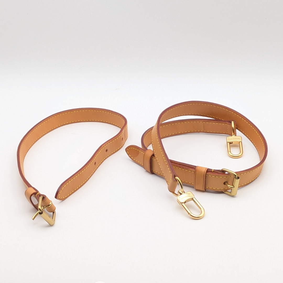Beige vachetta leather shoulder strap and extension piece with gold-tone clasps on a white background.