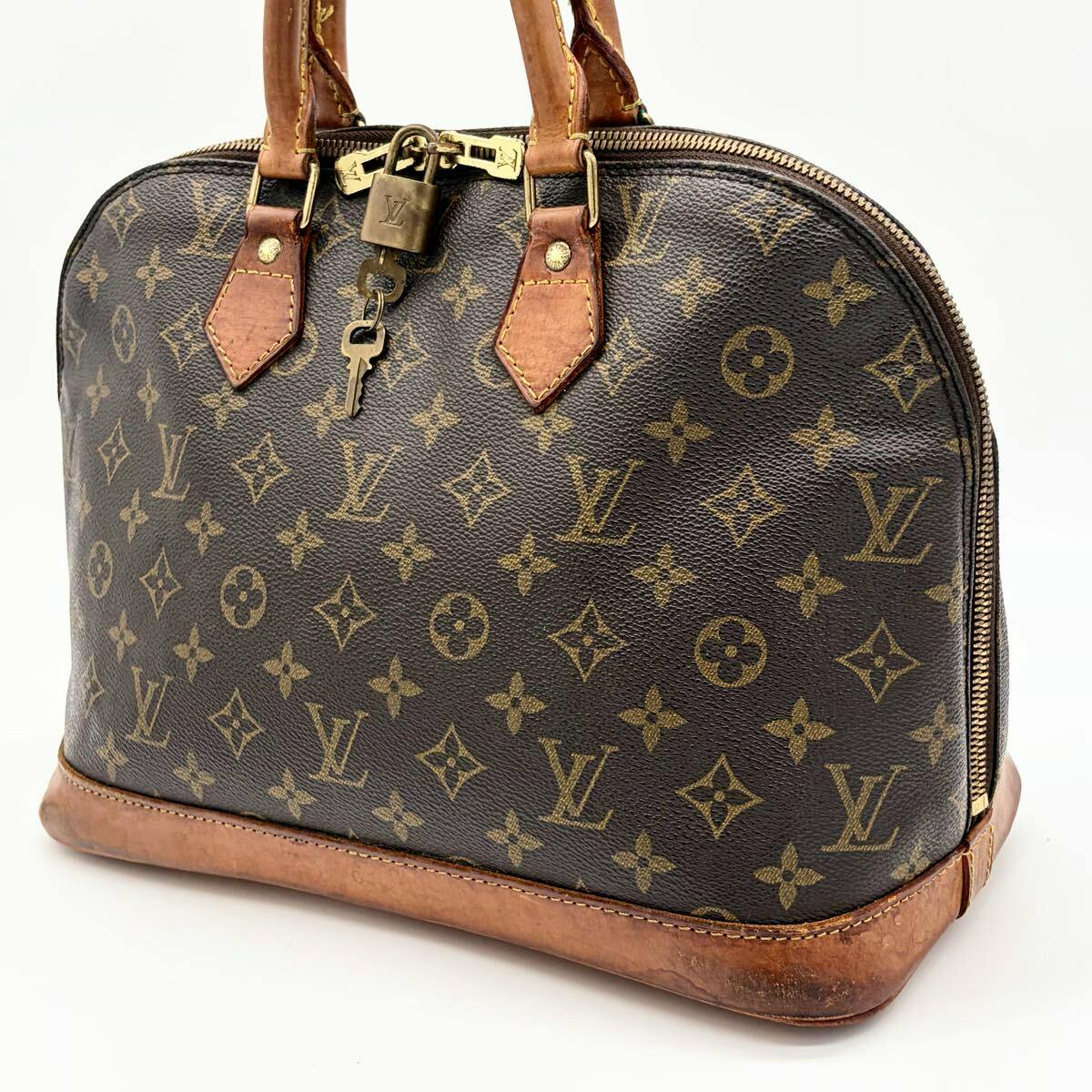 Brown Louis Vuitton Monogram Alma handbag with leather trim and gold-tone lock and keys visible on the front.