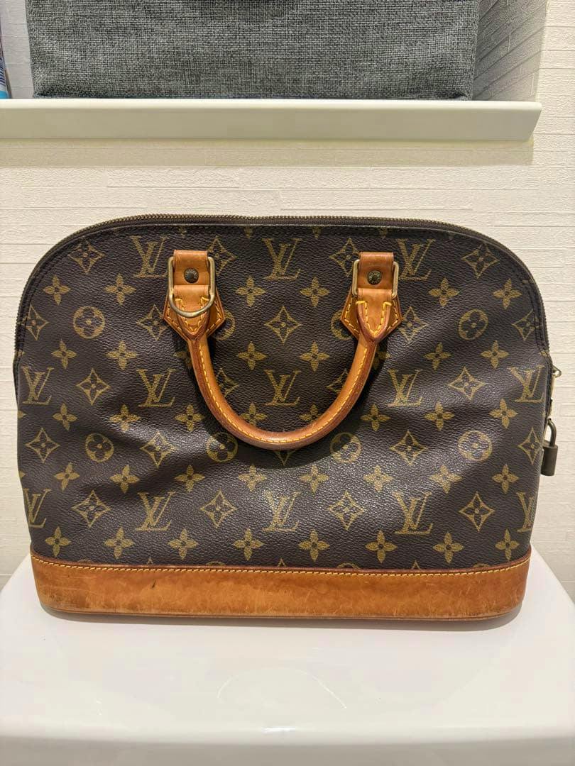 Front view of the LOUIS VUITTON Alma monogram handbag with cow leather base and handles.
