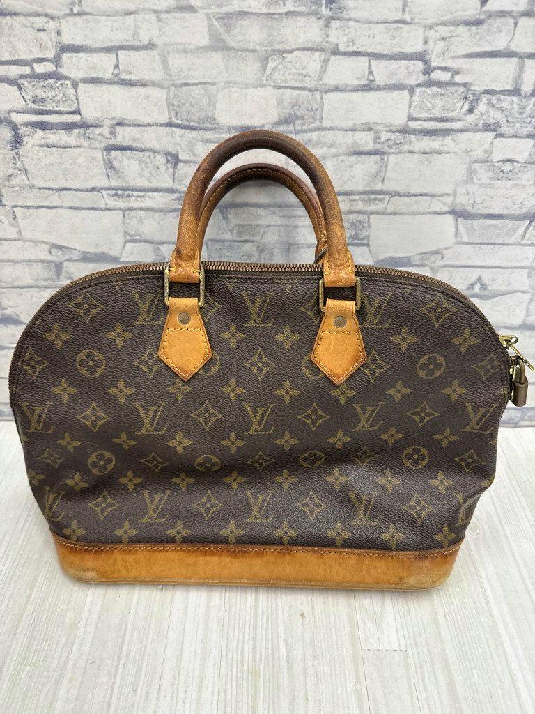 Front view of the Louis Vuitton Alma PM monogram brown handbag with leather handles and base.