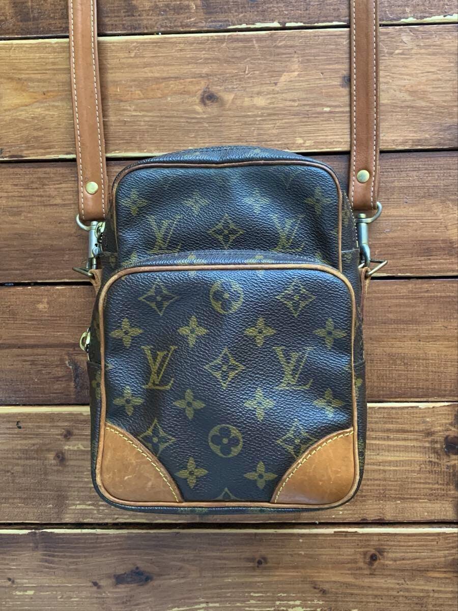 Front view of a Louis Vuitton monogram Amazon shoulder bag with leather trim and strap on a wooden surface.