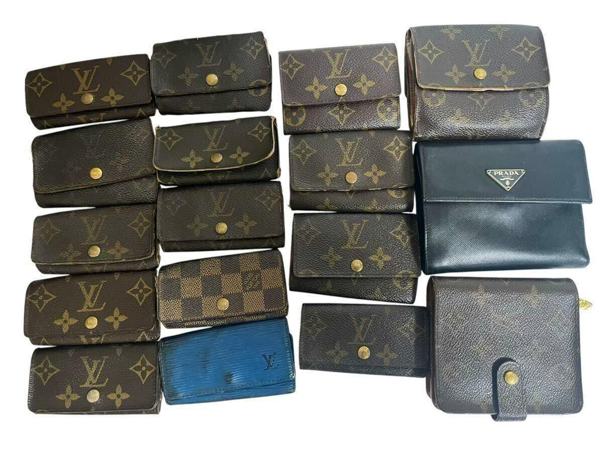 Multiple Louis Vuitton monogram and Damier canvas small wallets and one Prada wallet arranged on a white background.