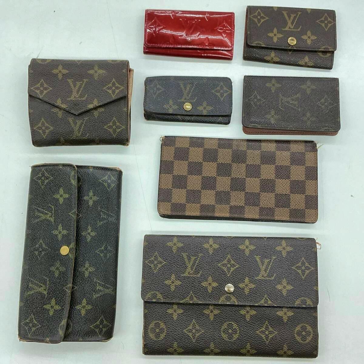 Eight used Louis Vuitton small wallets and accessories in brown monogram and Damier patterns arranged on a white surface.