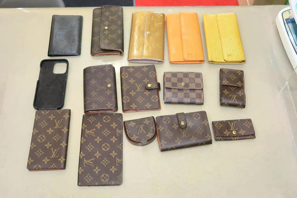 Assorted Louis Vuitton wallets and small leather goods arranged on a table showing monogram, Damier, and Epi patterns.