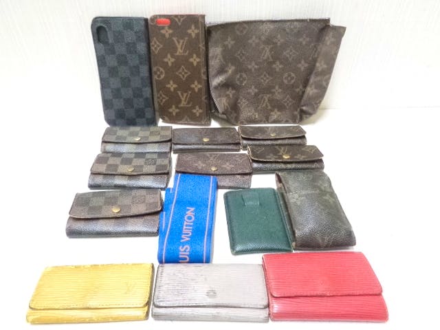 Multiple Louis Vuitton small leather goods including key cases and pouches in monogram, Damier, and Epi patterns arranged on a white surface.