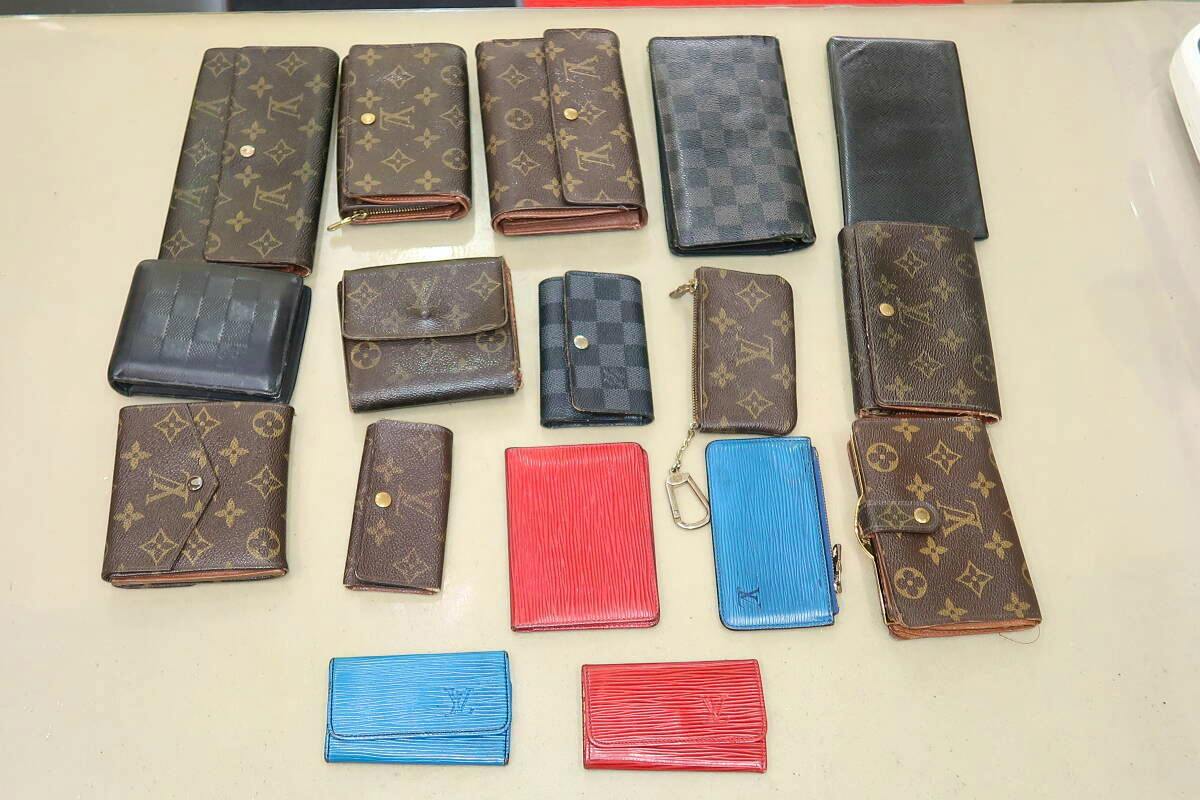 Several Louis Vuitton wallets and small leather goods arranged on a flat surface showing monogram, Damier, and colored pieces.