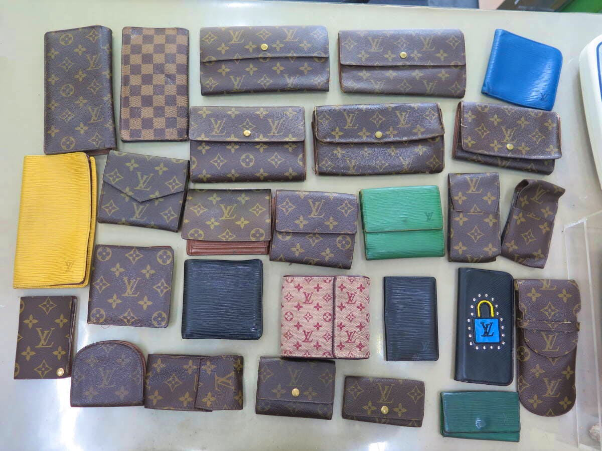 Multiple Louis Vuitton wallets and small leather goods in monogram and colored leathers laid flat on a table.